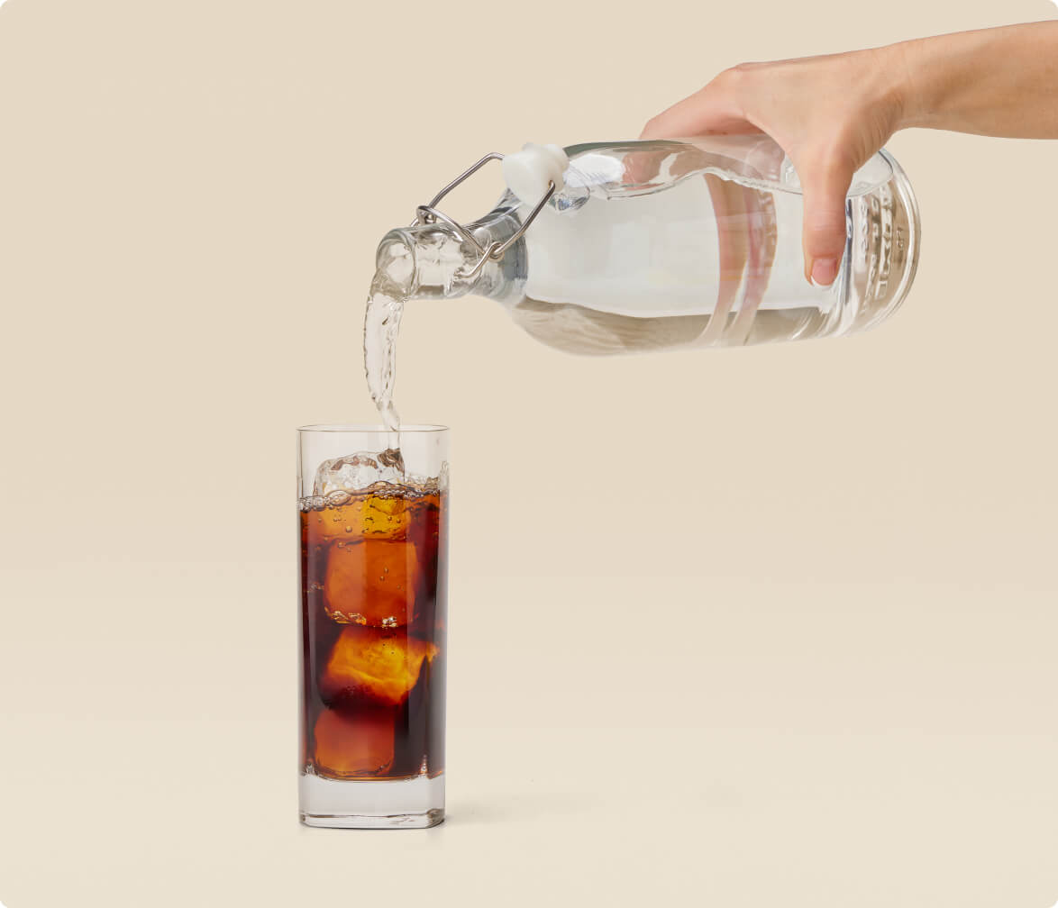 A person pouring expresso into a glass, creating a fizzy and refreshing beverage.